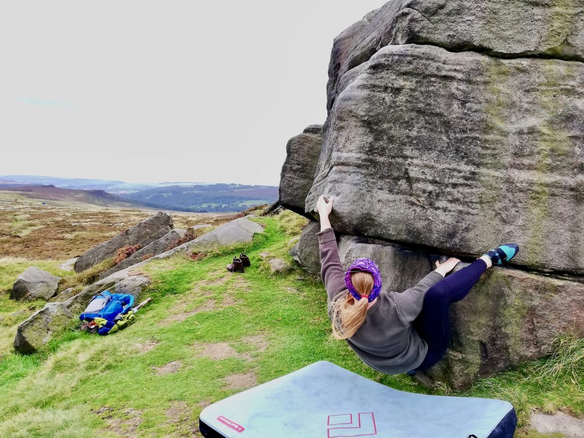 A woman outdoor bouldering at Stanage Edge in the Peak District